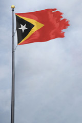 Worn and tattered East Timor flag blowing in the wind on a cloudy day
