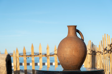 Large earthenware jug stands on a table on the shore near the sea water in Batumi, Georgia.