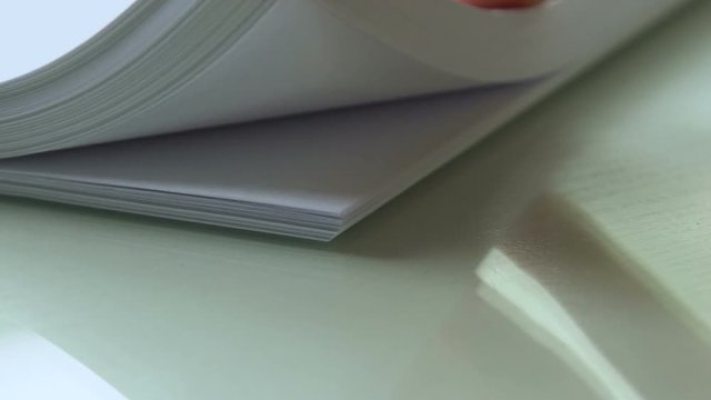 Hand leafing through thick white paper sheets, documentation, typography closeup
