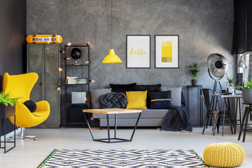 Yellow egg chair in modern living room interior with home office and comfortable sofa with pillows,...