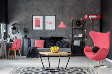 Rogue pink egg chair in dark scandinavian living room with home office and coffee table, real photo