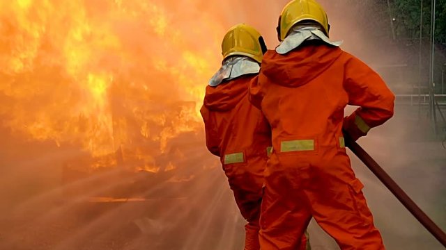 Slow motion : Fireman trying to stop flames at burnt car