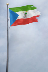 Obraz na płótnie Canvas Worn and tattered Equatorial Guinea flag blowing in the wind on a cloudy day