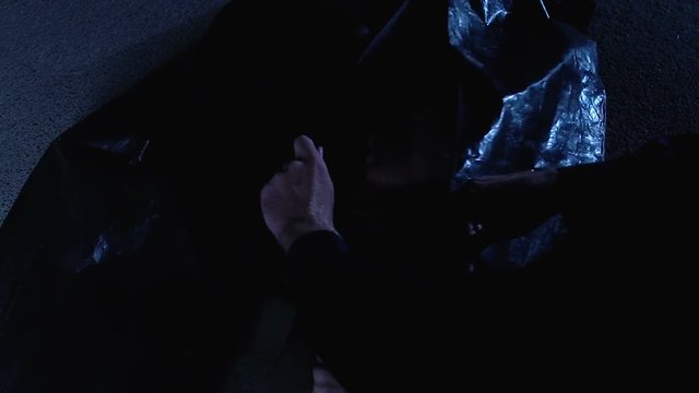 Police officer zipping body bag with dead young lady on crime scene at night