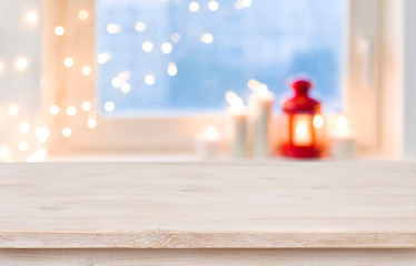 Wooden tabletop over blurred christmas lantern and candles on windowsill