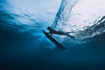 Surfer man with surfboard dive underwater of big ocean wave.