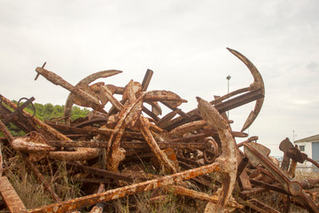 Stored old rusty ship anchors in rows in front of a Mediterranean landscape in Spain © were