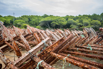 Stored old rusty ship anchors in rows in front of a Mediterranean landscape in Spain