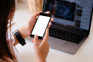 Mockup smartphone on hands working on office table with clipping path on display.