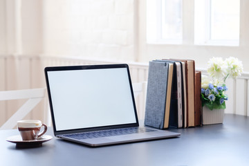 Mockup laptop and books with coffee on office desk.