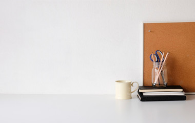 Coffee mug, notebook, pencil and office supplies with copy space on white table.