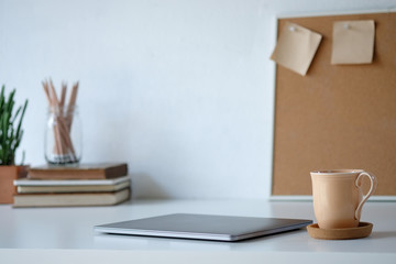 Mug of coffee and laptop on office desk.