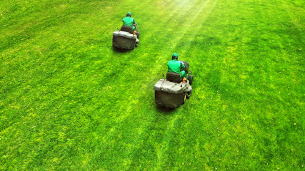 Aerial. Pair of lawn mowers on a grass. Professional gardening background with a two workers and...