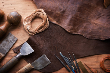 Leather craftmans work desk . Piece of hide and working tools on a work table.