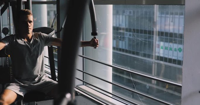 Young beginner man exercising in gym training with training apparatus