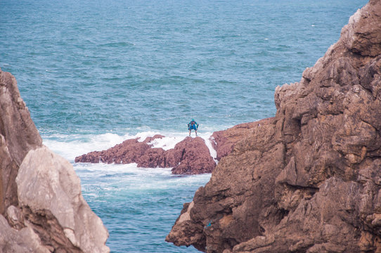 persona a lo lejos pescando percebes en el mar, copy-space