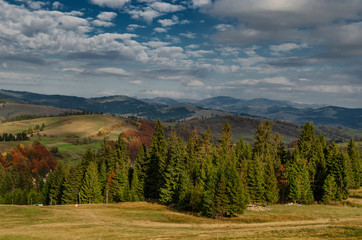 Fototapeta na wymiar Beautiful autumn landscape with mountain hills, yellow trees and blue skies.