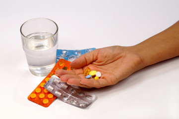 Feminine hand with a dose of medication on the background of packaging with pills.