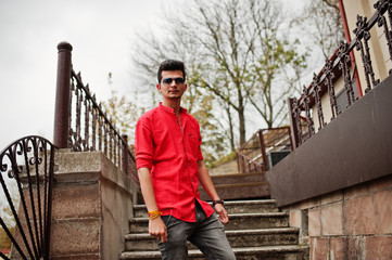 Fototapeta na wymiar Indian man at red shirt and sunglasses posed outdoor.