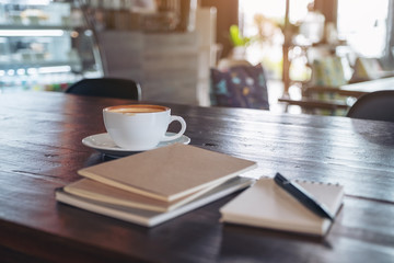 Notebooks, pen and coffee cup on wooden table in cafe