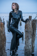 Portrait of Blonde Caucasian Girl Stays Smeared in a Healthy Black Mud in old Firth with Wooden...