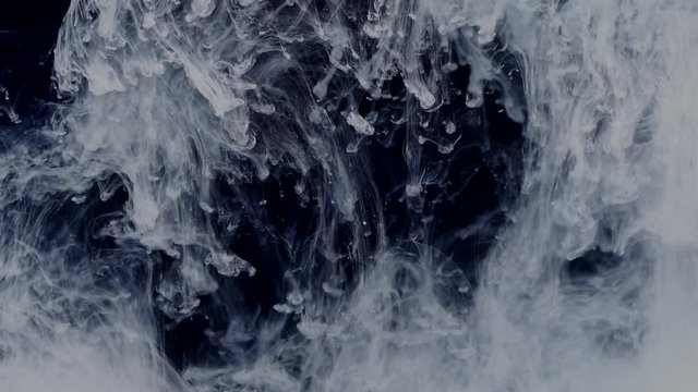 White and pastel colors in water on a black background make beautiful combinations. The explosion of white paint in water.