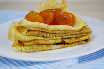 Delicious hot pancakes with apricot jam on a white plate.
