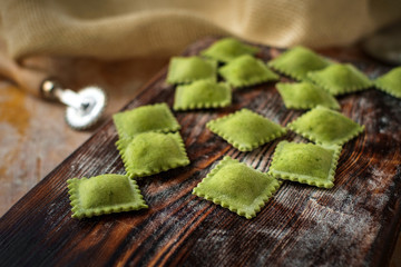uncooked homemade ravioli with flour on wooden background