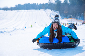 young smiling girl ride sleigh snow tubing hill winter activity