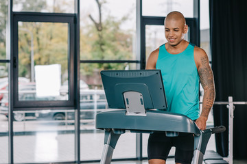 smiling african american male athlete on treadmill at gym