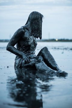 Portrait of an Adorable Caucasian Girl Sitting and posing Smeared with a Healthy Black Mud in old Firth