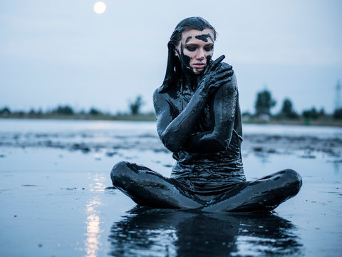 Portrait of an Adorable Caucasian Girl Sitting and posing Smeared with a Healthy Black Mud in old Firth
