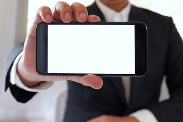 Businessman holding smartphone forward empty white screen for your text or picture.