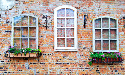 Brick wall of the house with stylized Windows and flowers in the basket