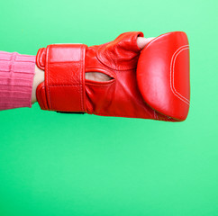  hand is wearing a red leather boxing glove on a green background