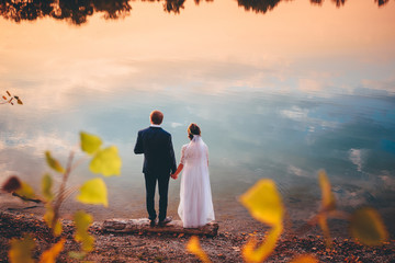 Wedding photo - bride and groom by blue lake in sunset light