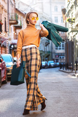 Outdoor full body fashion portrait of young fashionable girl wearing autumn outfit: glasses,...