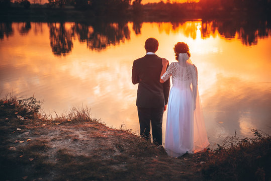 Bride and groom, sunset by autumn lake