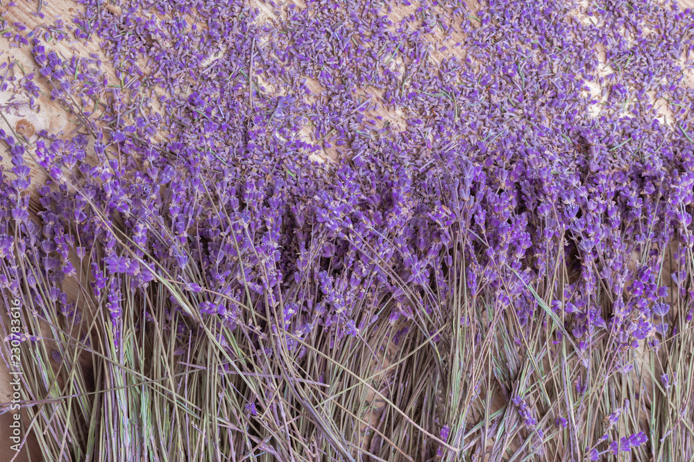 Wall mural lavender dried flowers scattered and bunch on rustic wooden background top view closeup