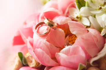 two gold wedding rings lie on a bouquet of flowers, close-up