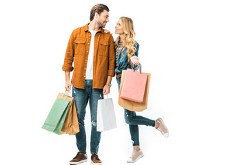 couple holding colorful shopping bags and looking at each other isolated on white
