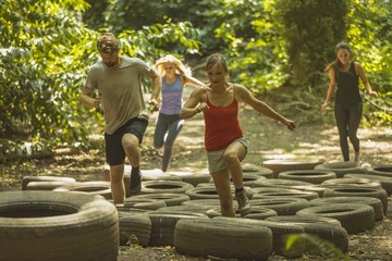 Group of people running over tires during obstacle course