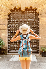 woman traveler with backpack standing at the old door entrance © EdNurg