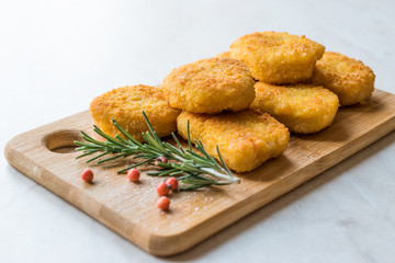 Homemade Crispy Chicken Nuggets with Rosemary and Cranberries on Wooden Board.