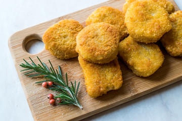 Homemade Crispy Chicken Nuggets with Rosemary and Cranberries on Wooden Board.