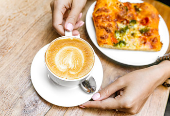 Woman eating focaccia Pizza and Coffee on wooden table in cafe