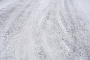 Fototapeta na wymiar Multiple cars tire tracks in the snow on asphalt road
