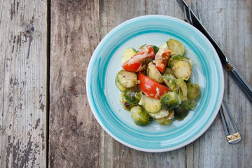 Bunch of fresh Bruxelles sprouts in plate on rustic wooden background. Healthy food.