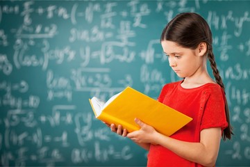 Cute little schoolgirl in glasses on blackboard
