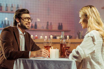 happy couple celebrating at table with candles and wine glasses in restaurant